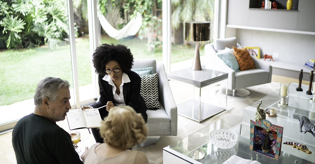 An escrow agent meets with her clients in a home