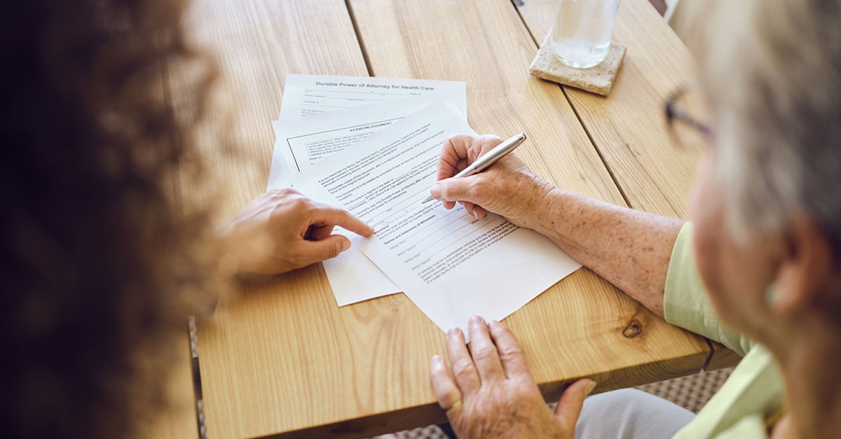 An elderly woman signing documents related to her will